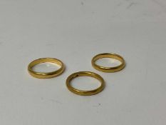 Three 22ct gold wedding bands, ring sizes J 1/2, K and M1/2 (3)
