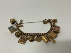 9ct gold charm bracelet with heart shaped padlock clasp and twelve gold and yellow metal charms.