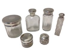 Group of six silver-topped glass bottles and jars, including a set of three with engine-turned decor