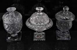 Group of three 19th century cut glass sweetmeat urns and covers, of varying shapes, 18cm to 18.5cm h