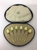 A cased set of six yellow-enamelled and silver-gilt teaspoons, Birmingham 1922