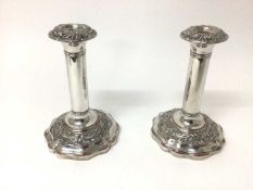 Pair of Victorian silver plated candlesticks with foliate scroll decorated borders and shaped bases,