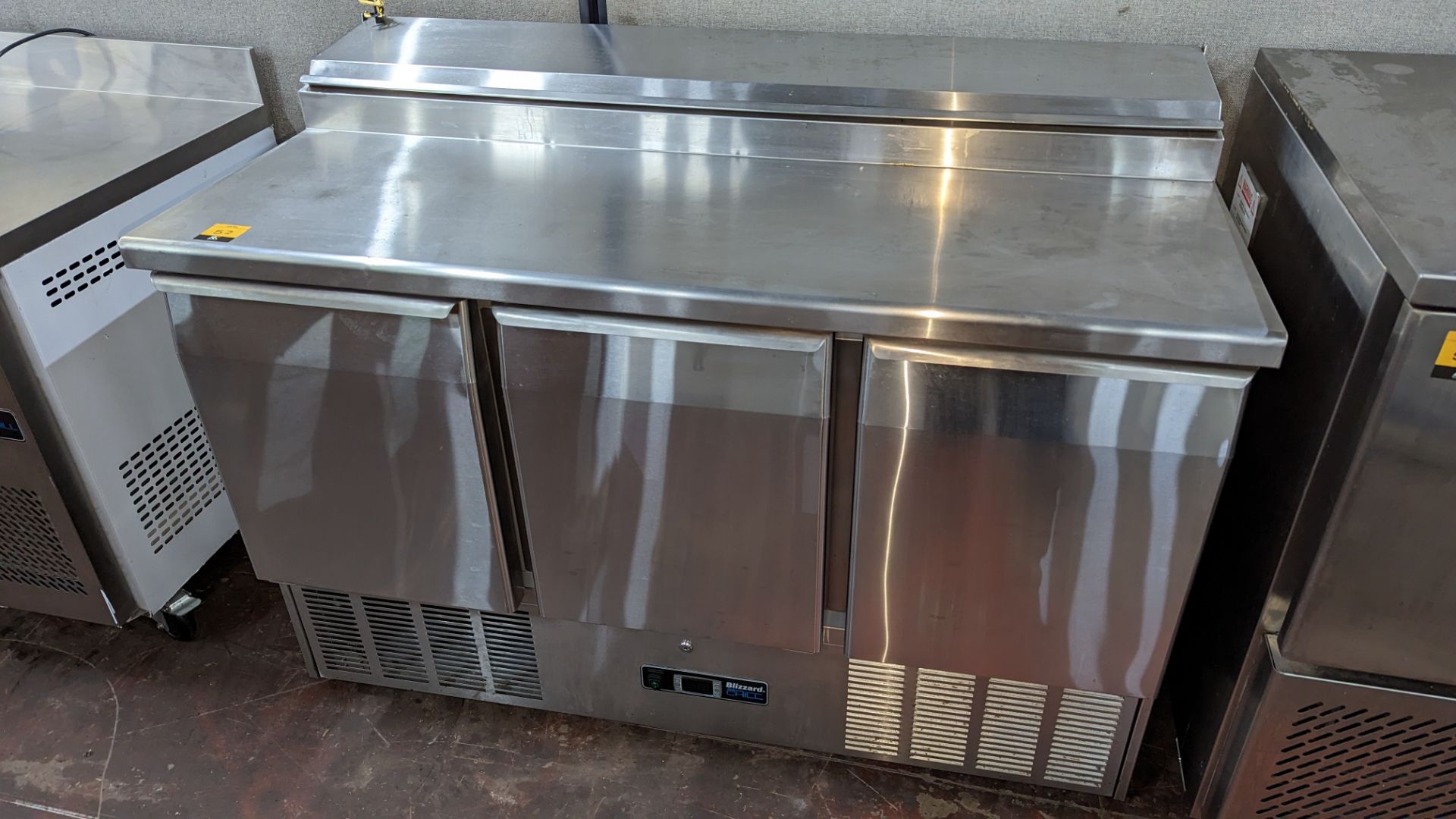Blizzard stainless steel refrigerated 3 door prep unit with hinged access to saladette unit at rear.