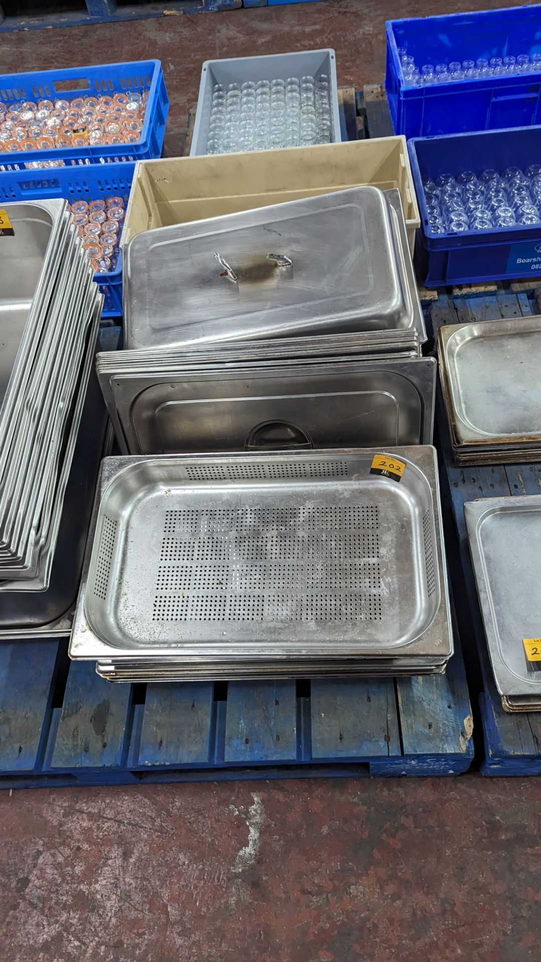 Row of assorted stainless steel trays including perforated & lids for use with same - approximately