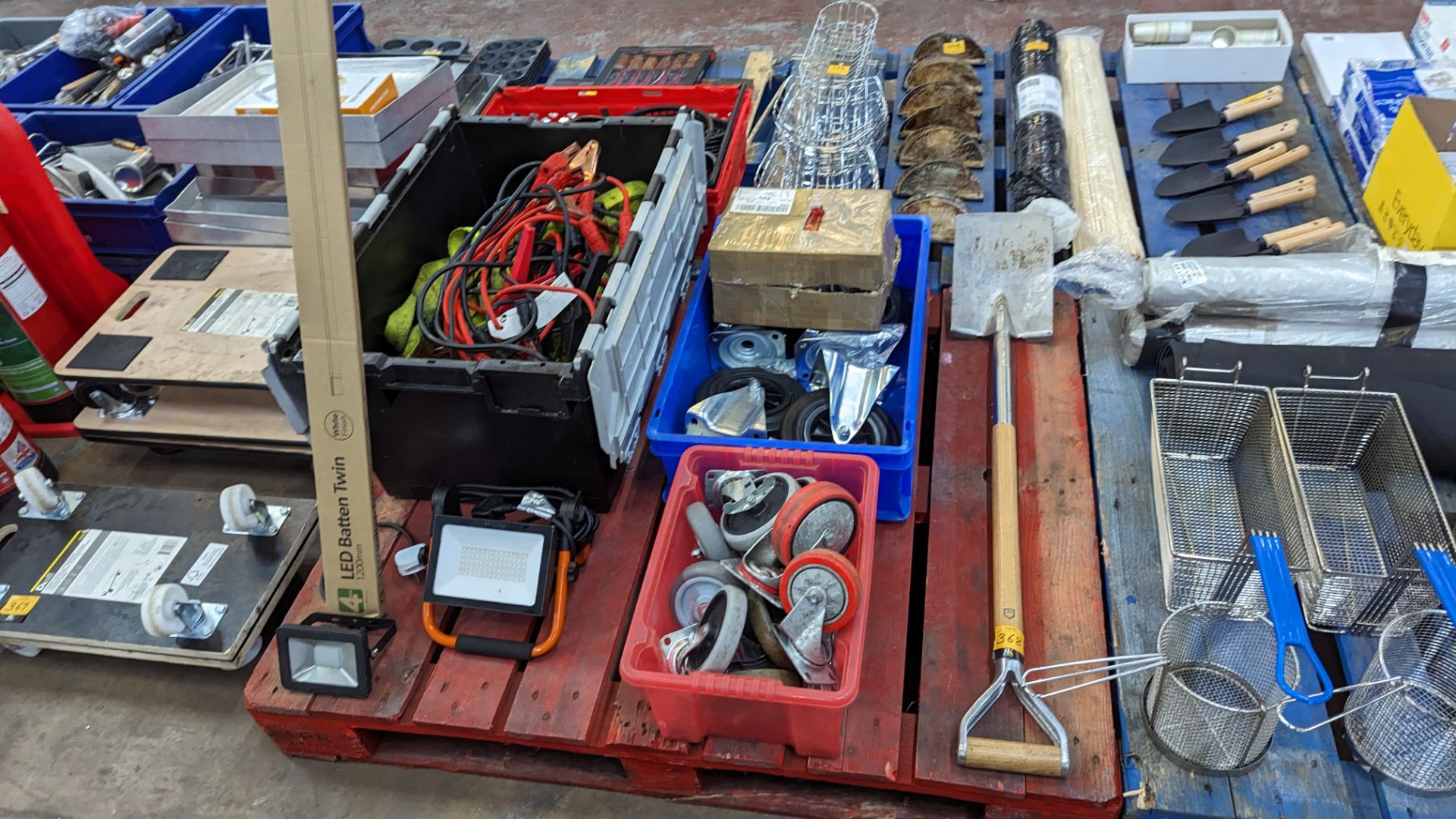 The contents of a pallet including long handle spade, jump start cables, safety harnesses, wheels, l