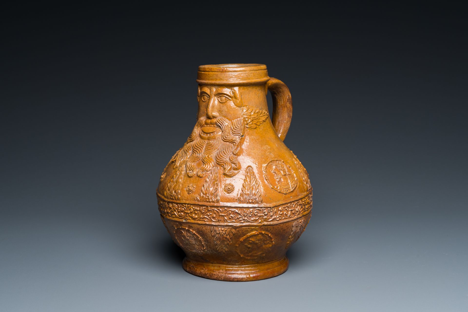 A rare German stoneware bellarmine jug with a bearded face sticking his tongue out, Cologne, 16th C.