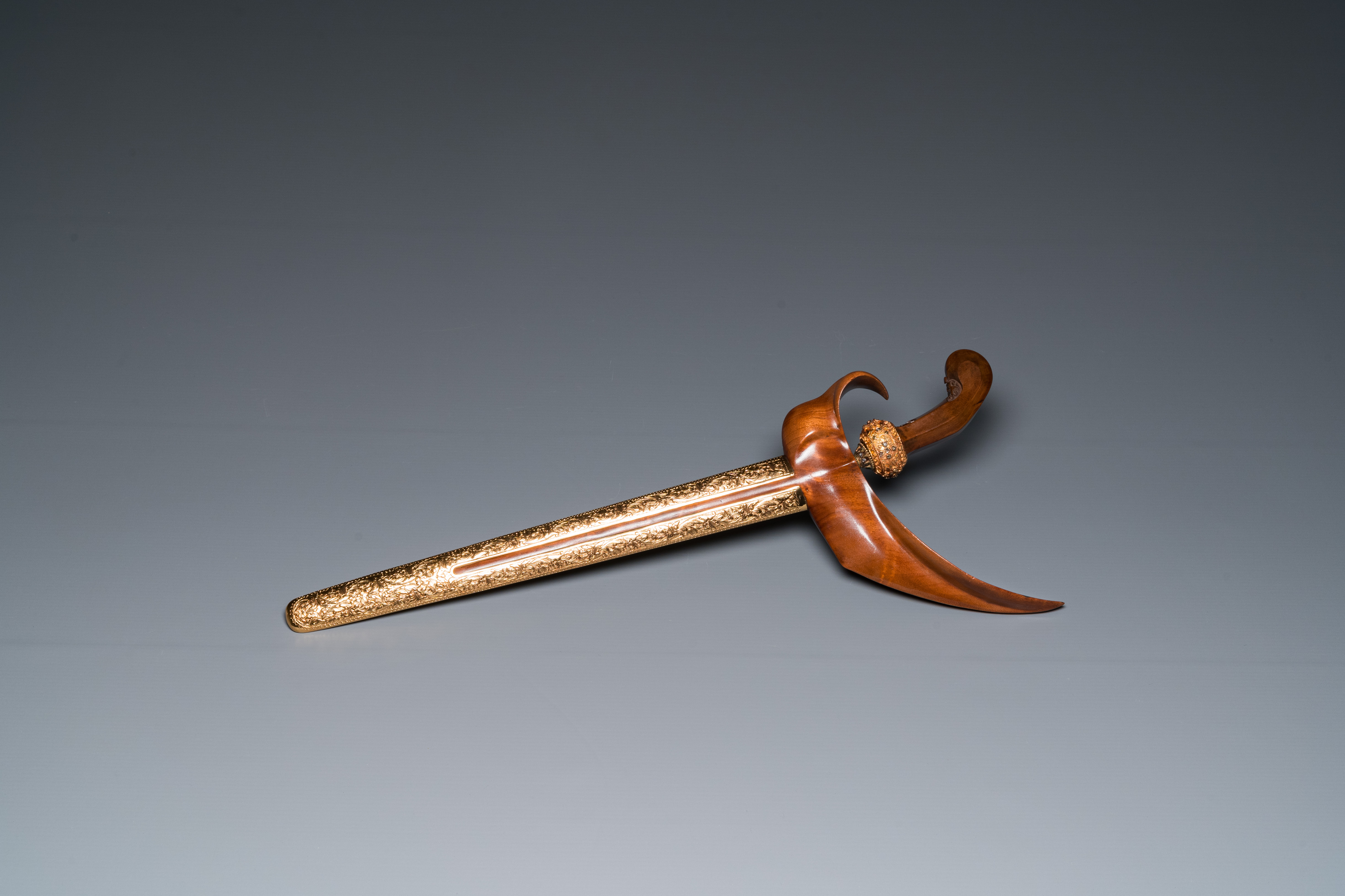 An Indonesian 'kris' or 'keris' dagger in polished Javanese wood with gold, gilt silver and precious