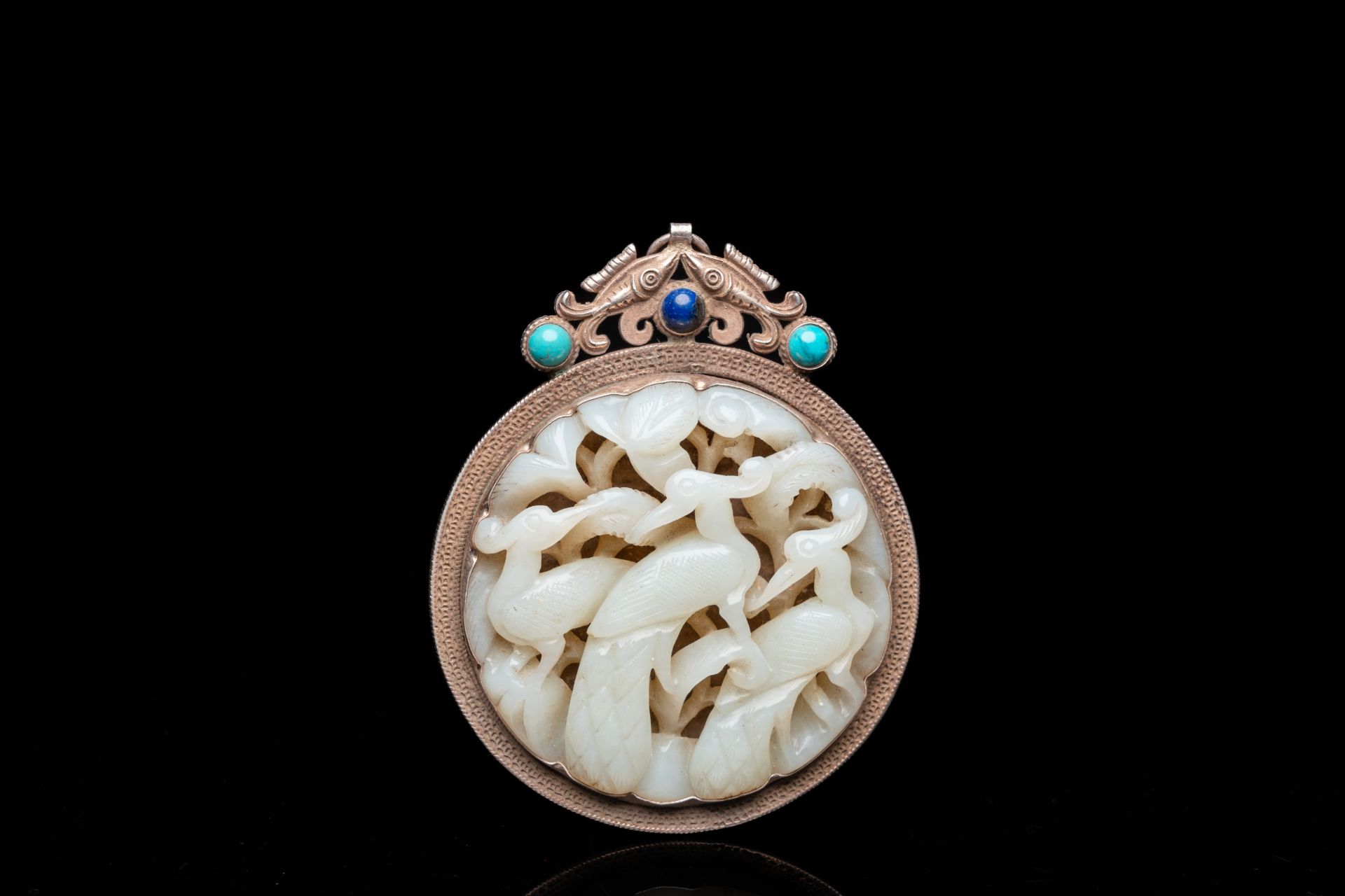 A Chinese reticulated jade 'three peacocks' carving in silver pendant, Qing