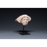 A Greek terracotta with white engobe antefix in the shape of a woman's head, 5/4th C. b.C.