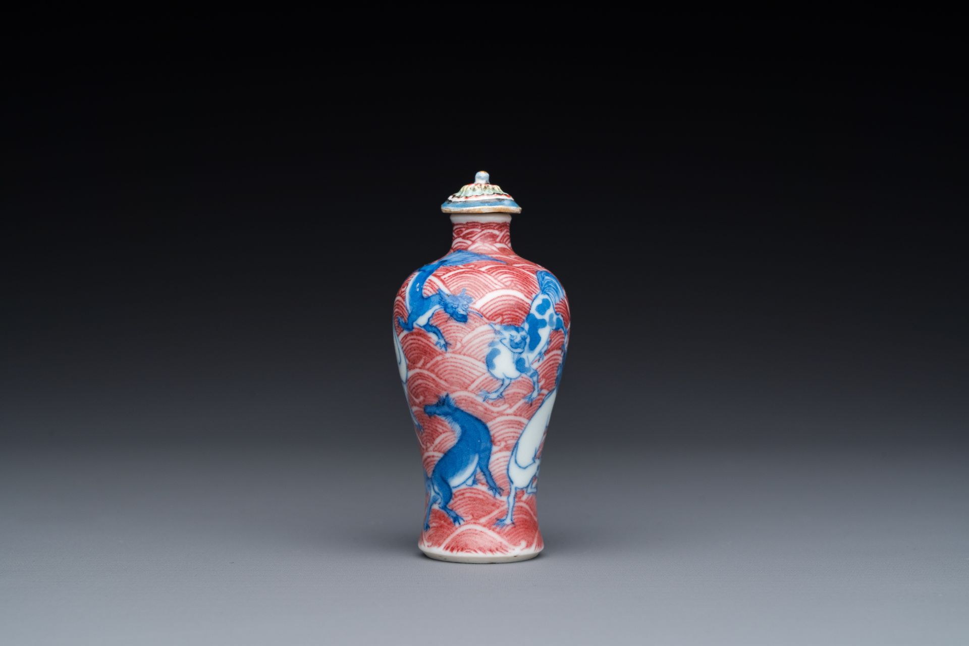 A Chinese blue, white and copper-red 'dogs' snuff bottle, 19th C.