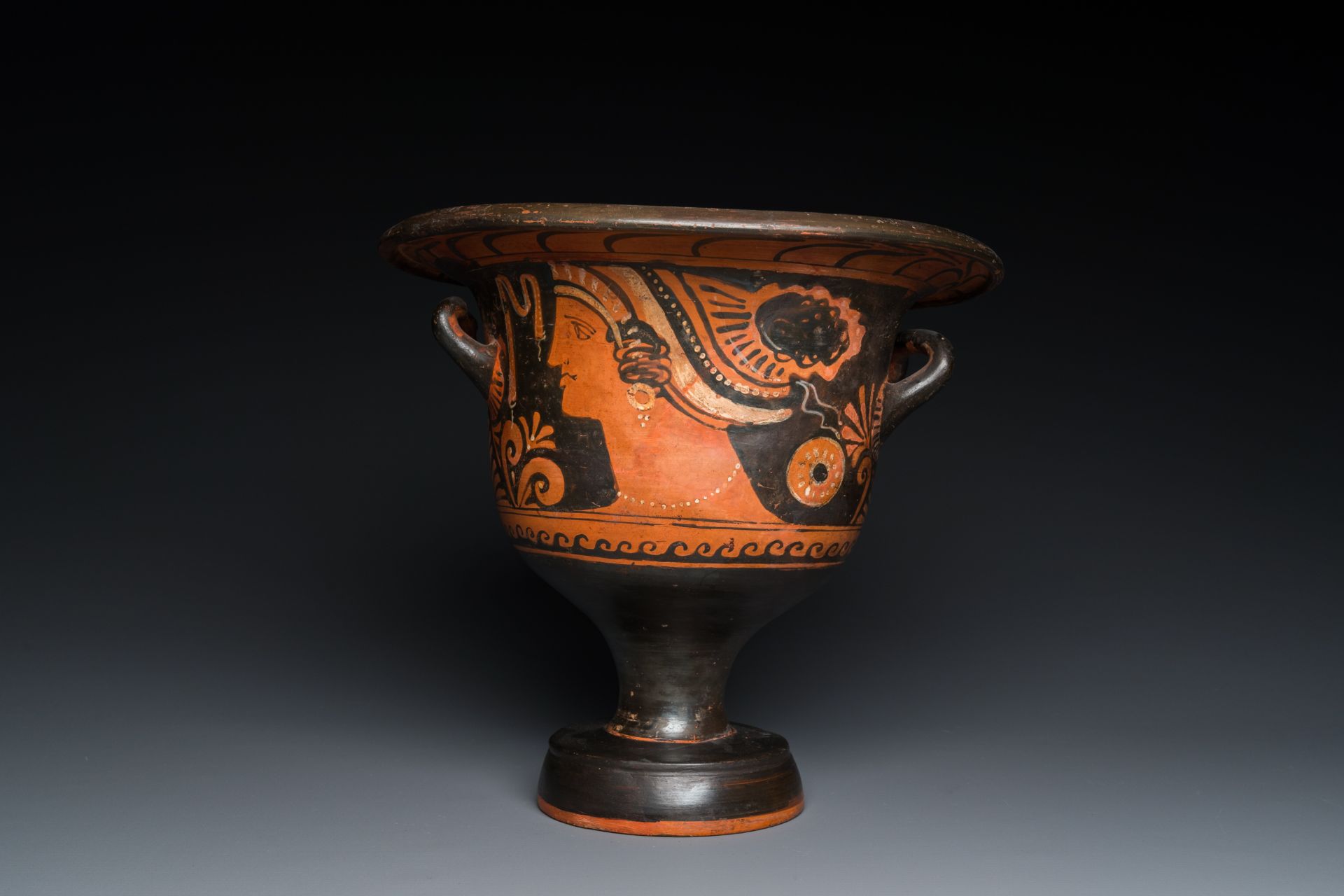 A Greek Apulian red figure bell krater with a winged female and a lady's head, 4th C. b.C.