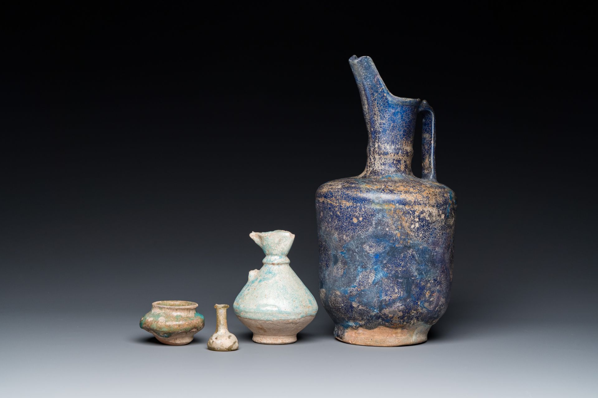 Three blue- and turquoise-glazed Islamic pottery wares and a glass bottle, Kashan and Raqqa, 12th C.