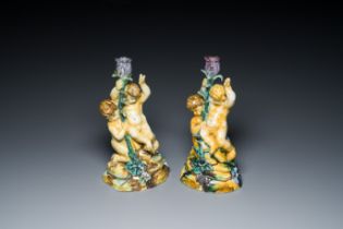 A pair of polychrome Talavera pottery candlesticks with putti on a branch, Spain, 18th C.