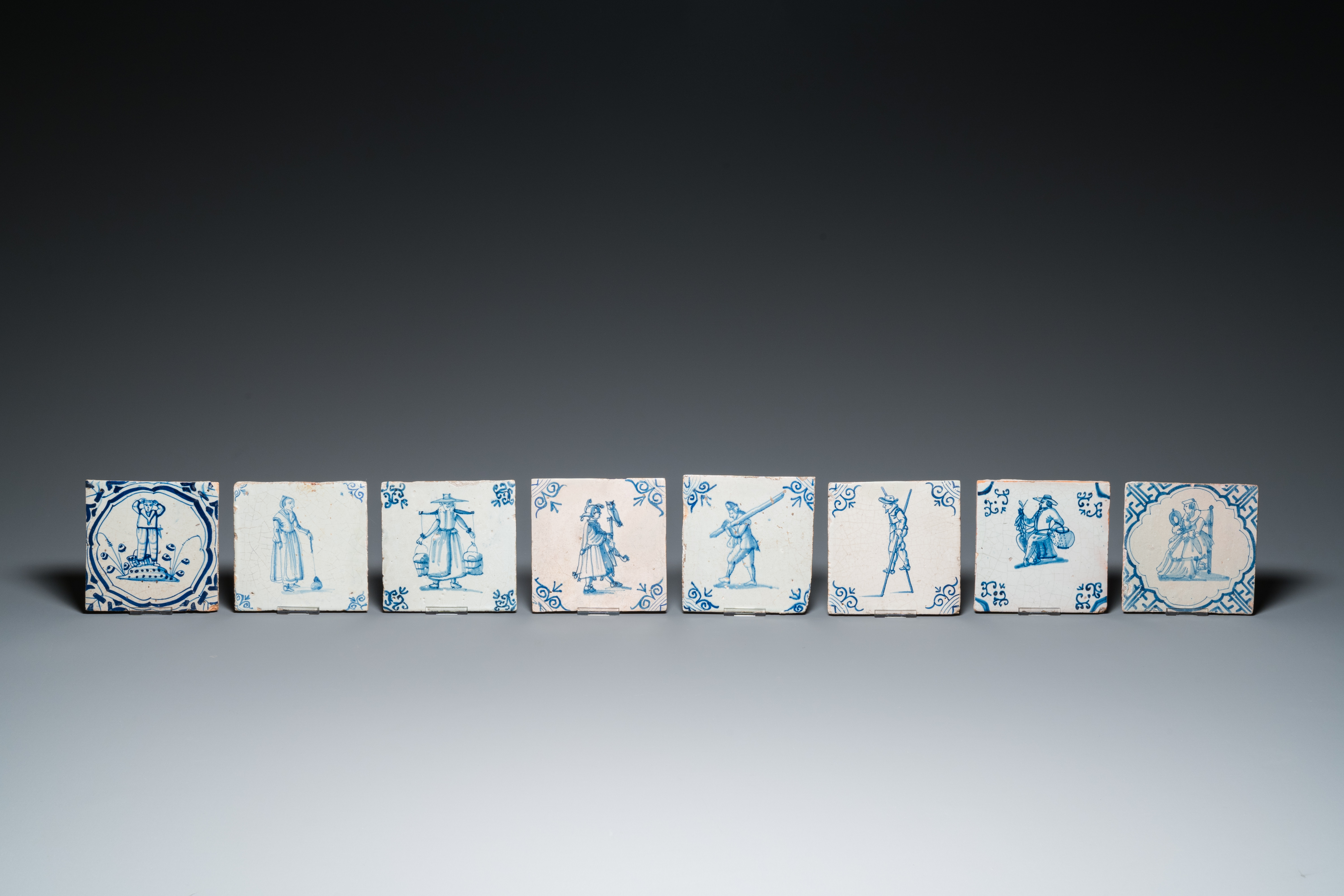 Eight Dutch Delft blue and white tiles with a jester, craftsmen at work and playing children, 17th C - Image 2 of 3