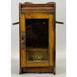 EDWARDIAN OAK SMOKER'S CABINET - folding pipe holders to side, glazed door enclosing interior fitted