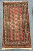 A TEKKE BOKHARA RED GROUND RUG - with typical repeating gul design, 170 x 96cms