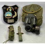 A GAS MASK IN CLOTH BAG, a sheath knife with 19cms blade and a wall plaque, Saigon Flyer, D McNiff