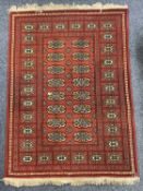 A TEKKE BOKHARA RED GROUND RUG - with typical repeating gul design, 156 x 112cms