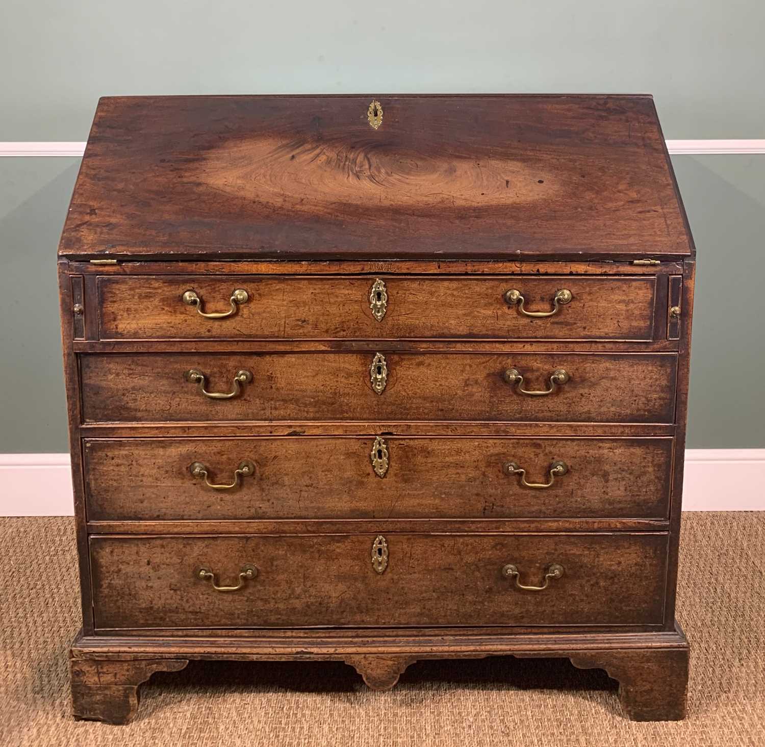 GEORGE III MAHOGANY BUREAU, angled fall enclosing fitted interior, above four graduated long