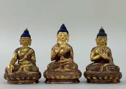 THREE SMALL GILT COPPER FIGURES OF BUDDHA, seated on double lotus thrones with hands held in