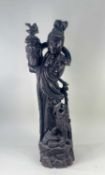 CHINESE CARVED WOOD SCULPTURE OF GUANYIN, standing in flowing robes holding a vase, Dog of Fo at her