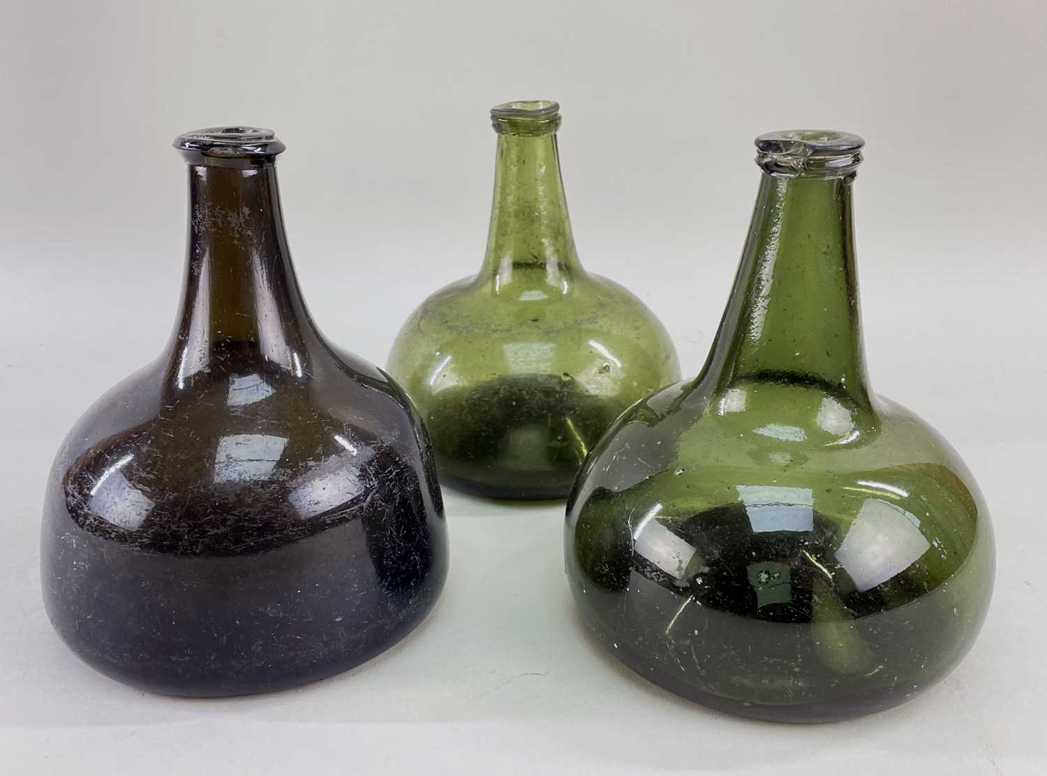 THREE GLASS 'ONION' WINE BOTTLES, 2 olive green, 1 forest green, all compressed, 18th Century,