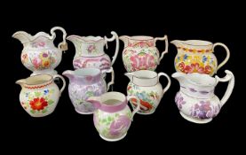 NINE ANTIQUE FLORAL PAINTED / LUSTRE DECORATED JUGS including Swansea Glamorgan, one with restored