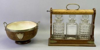 EDWARDIAN OAK 3 BOTTLE TANTALUS with EPNS mounts containing three square glass decanters with