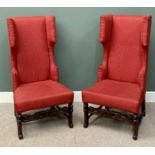 20th CENTURY HIGHBACK WING ARMCHAIRS - a pair in red upholstery, on carved supports and turned