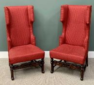 20th CENTURY HIGHBACK WING ARMCHAIRS - a pair in red upholstery, on carved supports and turned