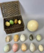 AN OSTRICH EGG, 39cms diameter and a basket containing 14 polished hardstone eggs