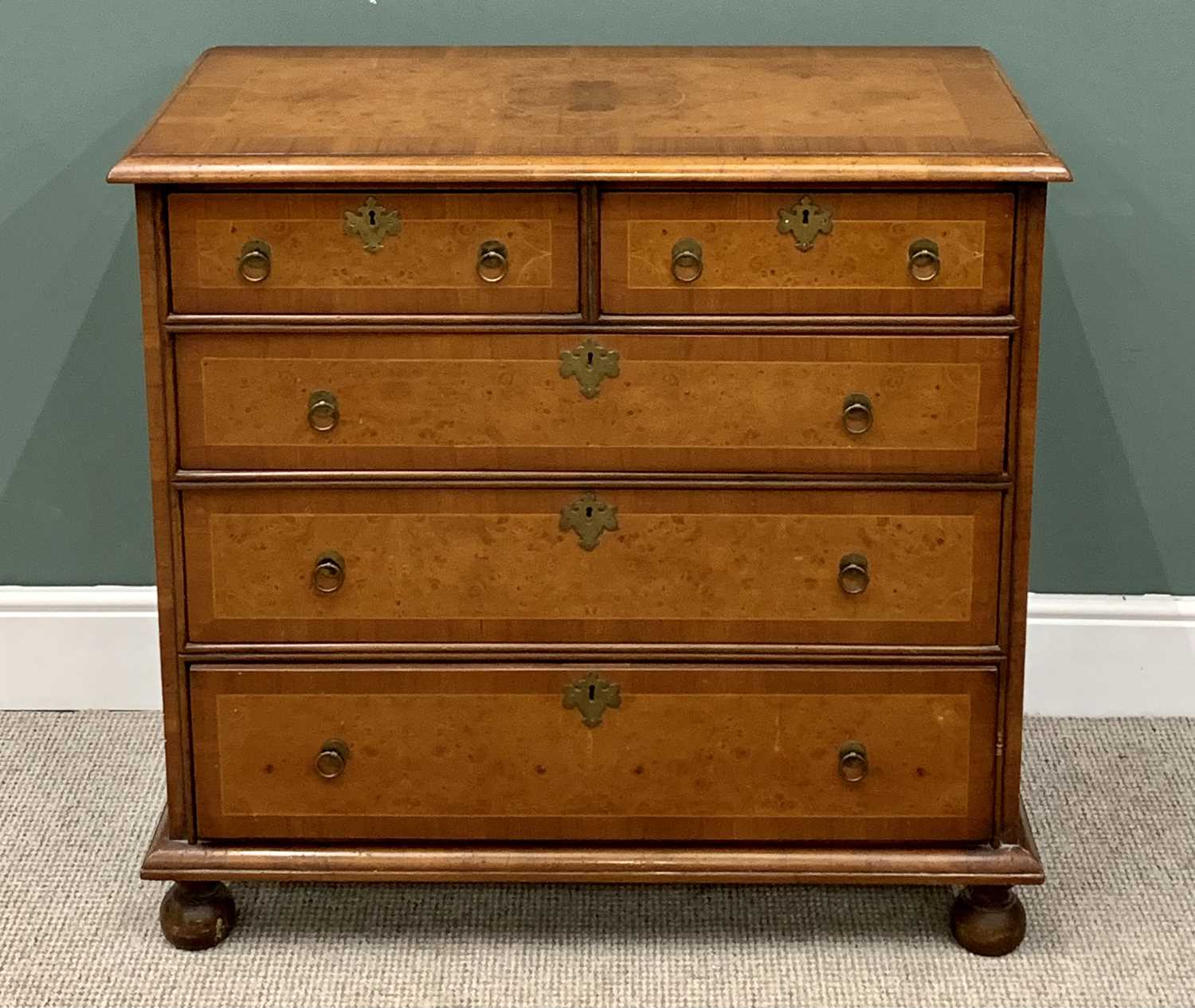 CROSSBANDED WALNUT CHEST OF DRAWERS - having two short over three long drawers with brass ring