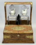 EDWARDIAN OAK TWO BOTTLE TANTALUS - with brass mounts and side carry handles containing two square