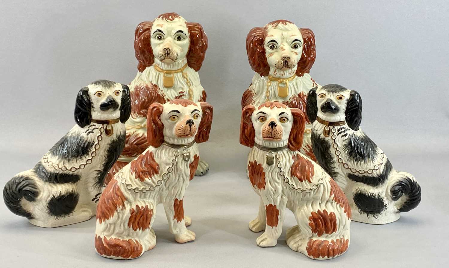 SEATED STAFFORDSHIRE SPANIELS, 3 PAIRS - 20th century, a pair with open front legs, molded fur,