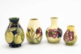 FOUR MOORCROFT POTTERY VASES, comprising three yellow ground 'Anemone' vases and an 'Apples' vase,