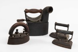 FOUR VICTORIAN FLAT IRONS & WORKSPLATE, comprising two conventional smoothing irons, another boat