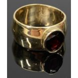 9CT GOLD BROAD BAND RING - set with an oval cut garnet, Size O, 7.9grms