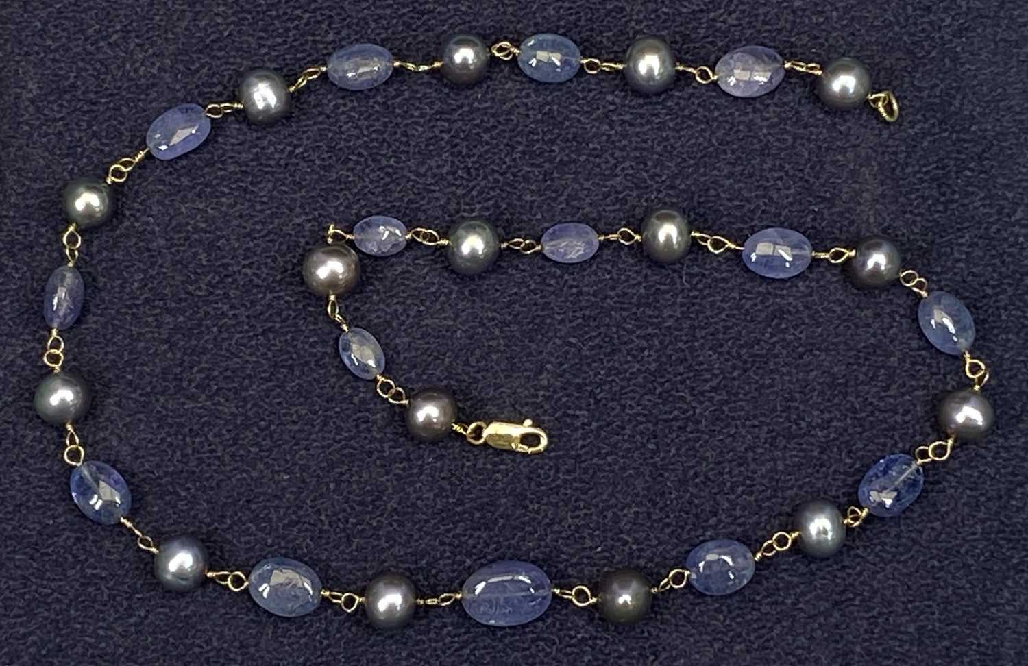 18CT GOLD TANZANITE & GREY PEARL NECKLACE BY DOWER & HALL stamped '750' to the lobster clasp, having