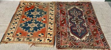 TWO EASTERN STYLE RED GROUND RUGS - one having bordered edging with traditional central pattern