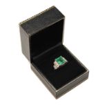 WHITE METAL DIAMOND & EMERALD RING, the central step cut emerald (10 x 8.5 x 6mms approx.) in corner