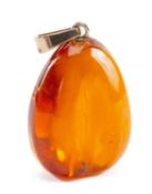 LARGE AMBER PENDANT, of pebble form with flute-polished sides, yellow metal suspension loop (