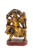 CHINESE LACQUERED WOOD FIGURE, Qing Dynasty, seated on a tiger and grasping the beard of a chilong