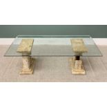 STYLISH MODERN COFFEE TABLE having bevelled edge glass top on antiquities-style stoneware plinths,