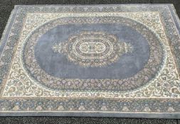 LARGE EASTERN STYLE WOOLEN RUG of blue ground with multiple borders and oval outline to the