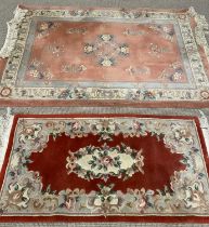 TWO CHINESE WASHED WOOLLEN RUGS, a red ground example with traditional floral motif and border
