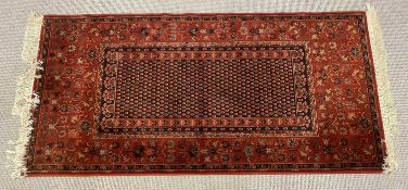 EASTERN STYLE RED GROUND RUG with central repeat pattern block and wide repeating pattern border