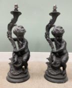 PAIR OF COMPOSITION CHERUBIC BLACK LAMPS, the figures seated holding leaf form fitting mounts on