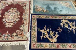 THREE CHINESE WASHED WOOLLEN RUGS, the first being burgundy ground with central floral pattern and
