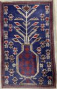 SMALL EASTERN WOOLLEN RUG, blue ground with large flowers in a vase central motif and Greek key-