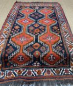 SOUTH CAUCASIAN RUG, two rows of conjoined hexagonal orange medallions with hooked edges, on navy